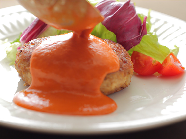 豆腐ハンバーグにソースをかけているイメージ