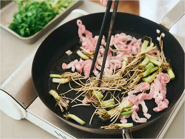 豚肉とせりの根を炒めているところ