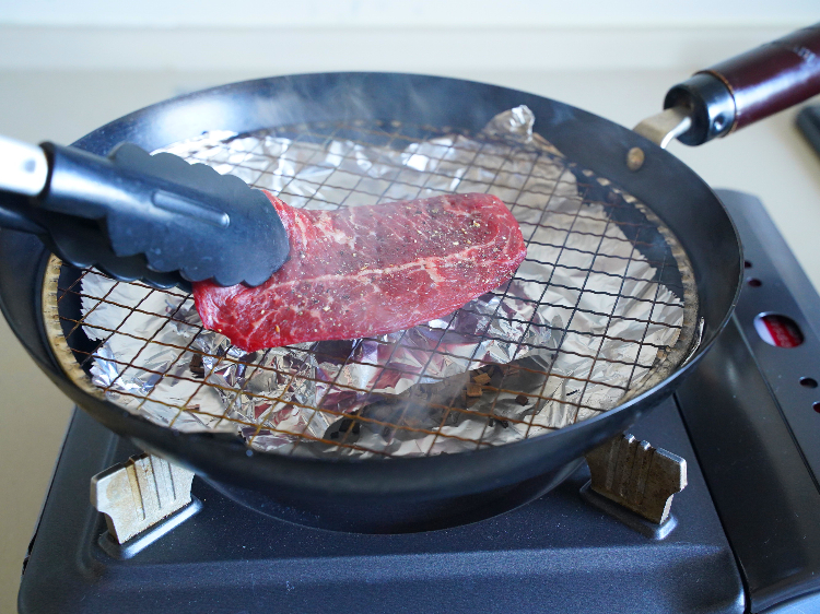 煙が立ったところに肉を入れる様子