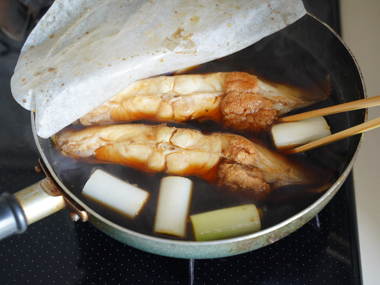 カレイを煮ている途中で長ねぎを加える様子