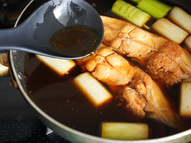 カレイの煮付けに煮汁をかける様子