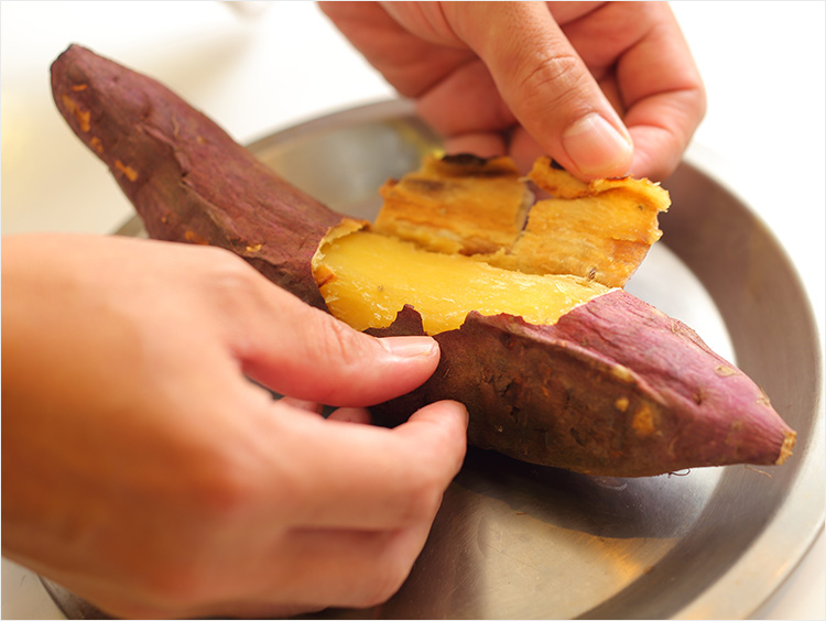 焼けたさつまいもの皮をむくイメージ